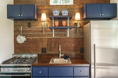 Small transitional single-wall dark wood floor kitchen photo in Atlanta with a drop-in sink, flat-panel cabinets, blue cabinets, wood countertops, stainless steel appliances and no island