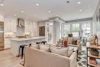 Large transitional single-wall light wood floor open concept kitchen photo in DC Metro with an undermount sink, flat-panel cabinets, white cabinets, marble countertops, white backsplash, mosaic tile backsplash, stainless steel appliances and an island