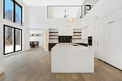 Open concept kitchen - large modern l-shaped bamboo floor and brown floor open concept kitchen idea in Chicago with flat-panel cabinets, white cabinets, quartz countertops, white backsplash, quartz backsplash, paneled appliances, an island and white countertops
