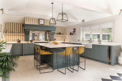 This is an example of a large eclectic l-shaped eat-in kitchen in Surrey with a farmhouse sink, shaker cabinets, grey cabinets, quartzite benchtops, mirror splashback, stainless steel appliances, limestone floors, with island, brown floor, white benchtop and exposed beam.