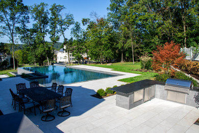 Example of a large trendy backyard tile and l-shaped infinity pool landscaping design in New York