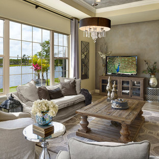 Mediterranes Wohnzimmer mit beiger Wandfarbe, freistehendem TV und braunem Boden in Orlando