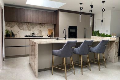 Inspiration for a medium sized contemporary grey and brown galley open plan kitchen in Manchester with a submerged sink, flat-panel cabinets, beige cabinets, engineered stone countertops, multi-coloured splashback, stone slab splashback, coloured appliances, porcelain flooring, an island, beige floors and multicoloured worktops.