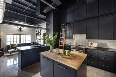 Exempel på ett mellanstort industriellt svart svart kök, med en undermonterad diskho, släta luckor, blå skåp, granitbänkskiva, vitt stänkskydd, stänkskydd i porslinskakel, rostfria vitvaror, en köksö och flerfärgat golv