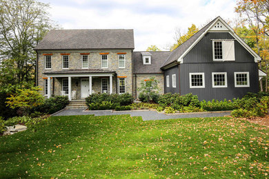 This is an example of a country two-storey grey house exterior with stone veneer.