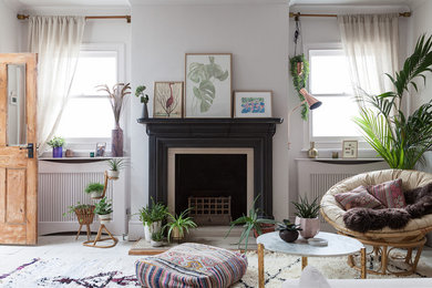 This is an example of a mid-sized eclectic open concept living room in London with white walls, painted wood floors, a standard fireplace, no tv and white floor.