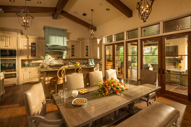 Inspiration for a large mediterranean l-shaped dark wood floor open concept kitchen remodel in Orlando with raised-panel cabinets, beige cabinets, granite countertops, multicolored backsplash, mosaic tile backsplash, stainless steel appliances and an island