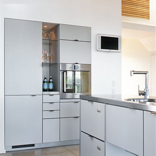 Contemporary kitchen pantry pictures - Trendy l-shaped concrete floor kitchen pantry photo in Wellington with a single-bowl sink, gray cabinets, stainless steel countertops, stainless steel appliances and an island