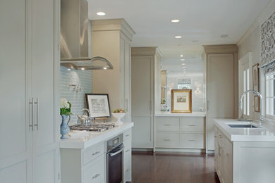 Photo of a traditional u-shaped kitchen in Oxfordshire with recessed-panel cabinets, grey cabinets, dark hardwood flooring, a submerged sink, blue splashback, glass tiled splashback, stainless steel appliances and no island.
