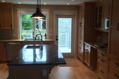 Large arts and crafts light wood floor eat-in kitchen photo in Vancouver with an undermount sink, recessed-panel cabinets, granite countertops, stainless steel appliances, an island, medium tone wood cabinets, beige backsplash and stone slab backsplash