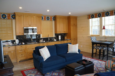 Example of an eclectic single-wall ceramic tile and beige floor open concept kitchen design in Cleveland with raised-panel cabinets, light wood cabinets, granite countertops, black backsplash, stone slab backsplash and stainless steel appliances