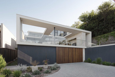 Large contemporary three-storey glass white house exterior with a flat roof and a metal roof.