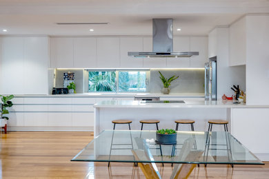 This is an example of a mid-sized contemporary galley eat-in kitchen in Perth with flat-panel cabinets, white cabinets, quartz benchtops, grey splashback, light hardwood floors and white benchtop.