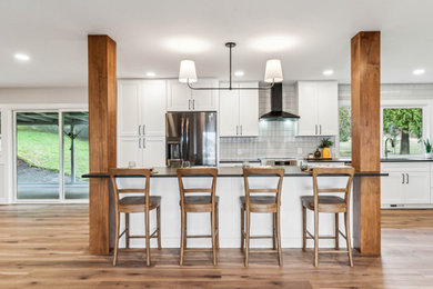 Mid-sized trendy single-wall vinyl floor and brown floor eat-in kitchen photo in Portland with a single-bowl sink, shaker cabinets, white cabinets, quartz countertops, white backsplash, ceramic backsplash, black appliances, an island and gray countertops