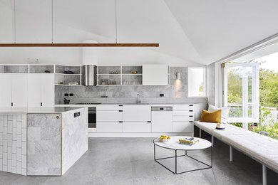 Beach style kitchen in Brisbane with flat-panel cabinets, white cabinets, grey splashback, concrete floors, with island, grey floor, grey benchtop and vaulted.