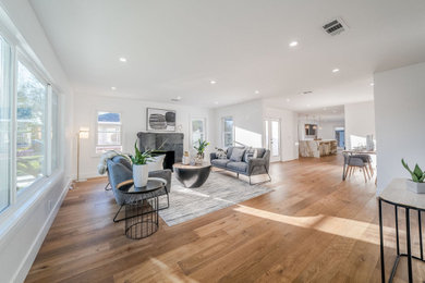Example of a large minimalist open concept light wood floor and brown floor family room design in San Francisco with white walls, a standard fireplace and a tile fireplace