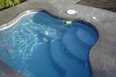 Backyard custom-shaped pool in Portland with a hot tub and concrete slab.