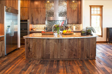 Photo of a mid-sized country eat-in kitchen in Other with flat-panel cabinets, dark wood cabinets, granite benchtops, stainless steel appliances, dark hardwood floors, with island, brown floor and beige benchtop.