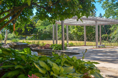 Design ideas for a mid-sized traditional full sun backyard stone pond in Other for summer.
