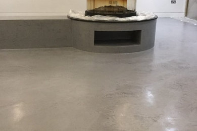 Imagen de salón para visitas cerrado de tamaño medio con paredes blancas, suelo de cemento, chimenea de doble cara, marco de chimenea de hormigón y suelo gris