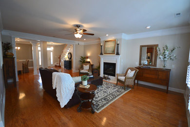 Living room - traditional open concept medium tone wood floor living room idea in Charleston with gray walls and a standard fireplace