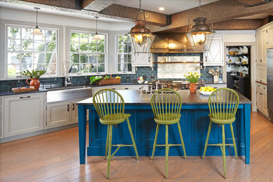 This is an example of a mid-sized traditional single-wall eat-in kitchen in Los Angeles with a farmhouse sink, beaded inset cabinets, blue cabinets, blue splashback, subway tile splashback, with island and medium hardwood floors.