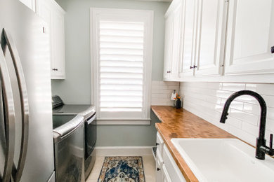 Mid-sized farmhouse galley dedicated laundry room photo in Dallas with a drop-in sink, white cabinets, wood countertops, white backsplash, subway tile backsplash, blue walls and a side-by-side washer/dryer