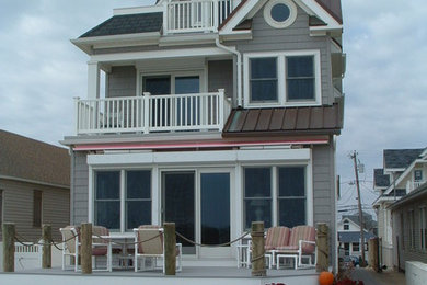 Example of a large beach style gray three-story vinyl exterior home design in New York