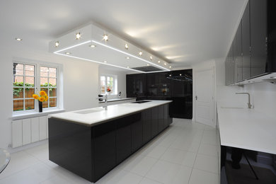 Design ideas for a large contemporary l-shaped separate kitchen in Other with an integrated sink, flat-panel cabinets, black cabinets, solid surface benchtops, white splashback, black appliances, porcelain floors and with island.