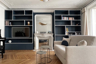 Idée de décoration pour un salon minimaliste de taille moyenne et ouvert avec une bibliothèque ou un coin lecture, un mur bleu, un sol en bois brun, une cheminée standard et un manteau de cheminée en pierre.