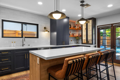 Mid-sized trendy l-shaped light wood floor and brown floor eat-in kitchen photo in Los Angeles with an undermount sink, shaker cabinets, blue cabinets, quartz countertops, white backsplash, porcelain backsplash, stainless steel appliances, an island and white countertops