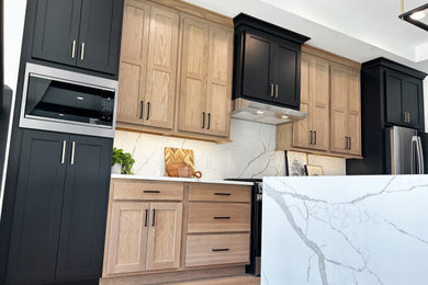 Example of a mid-sized mid-century modern single-wall light wood floor, brown floor and exposed beam open concept kitchen design in Other with an undermount sink, flat-panel cabinets, light wood cabinets, quartz countertops, white backsplash, quartz backsplash, stainless steel appliances, an island and white countertops