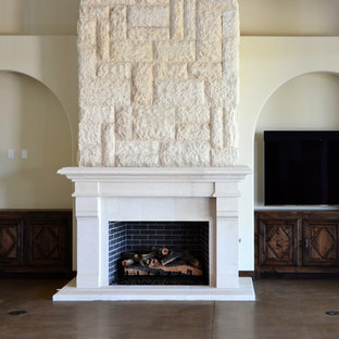 Großes Mediterranes Wohnzimmer mit beiger Wandfarbe, Betonboden, Kamin, Kaminsims aus Stein, Wand-TV und braunem Boden in Phoenix