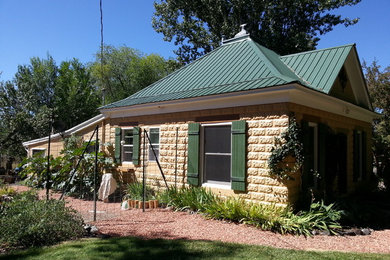 Inspiration for a mid-sized timeless beige one-story stone house exterior remodel in Denver with a hip roof and a metal roof