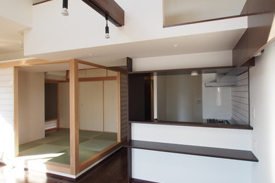 Design ideas for a modern kitchen/dining combo in Kobe with white walls, dark hardwood floors and brown floor.