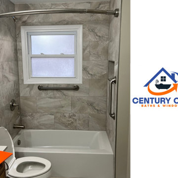 Bathtub and shower combo with marble-look tile, grab bars, and a privacy window.