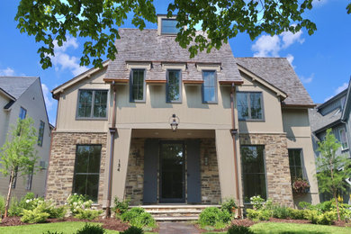 Large trendy beige three-story mixed siding house exterior photo with a mixed material roof