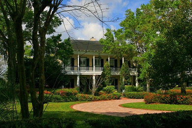 Inspiration for a large timeless yellow two-story stucco house exterior remodel in Orlando with a shingle roof