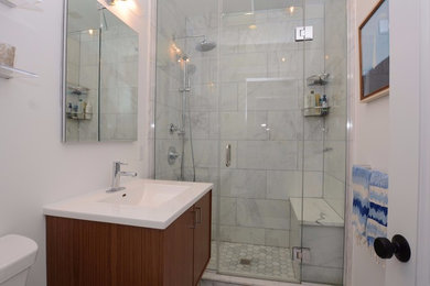 Alcove shower - mid-sized transitional gray tile, white tile and marble tile marble floor and white floor alcove shower idea in New York with flat-panel cabinets, dark wood cabinets, a two-piece toilet, white walls, solid surface countertops, a hinged shower door and an undermount sink