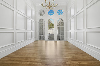 Inredning av ett stort allrum med öppen planlösning, med ett musikrum, vita väggar, mellanmörkt trägolv och brunt golv