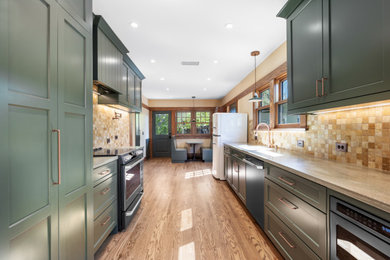 Inspiration for a mid-sized craftsman galley medium tone wood floor and brown floor kitchen remodel in Los Angeles with an integrated sink, flat-panel cabinets, green cabinets, brown backsplash, porcelain backsplash, colored appliances and beige countertops