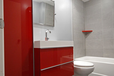 Example of a mid-sized minimalist kids' gray tile and porcelain tile porcelain tile bathroom design in New York with flat-panel cabinets, red cabinets, a two-piece toilet, blue walls, an integrated sink and solid surface countertops