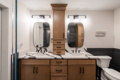 Bathroom - mid-sized master black and white tile and porcelain tile porcelain tile, black floor, double-sink and wall paneling bathroom idea in Philadelphia with shaker cabinets, medium tone wood cabinets, a two-piece toilet, white walls, an undermount sink, quartz countertops, a niche and a built-in vanity