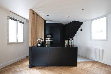 Inspiration pour une cuisine ouverte noire et bois design de taille moyenne avec des portes de placard noires, un plan de travail en granite, carreaux de ciment au sol, îlot, un sol beige et plan de travail noir.