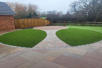Large modern back garden for spring in Sussex with a garden path and concrete paving.
