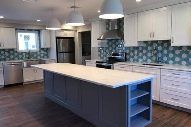 Inspiration for a huge modern l-shaped porcelain tile and brown floor enclosed kitchen remodel in New York with a farmhouse sink, shaker cabinets, white cabinets, quartzite countertops, multicolored backsplash, glass tile backsplash, stainless steel appliances, an island and white countertops