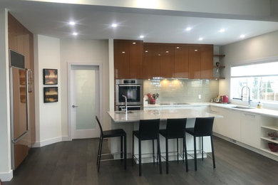 Example of a trendy u-shaped dark wood floor and brown floor eat-in kitchen design in Edmonton with an undermount sink, flat-panel cabinets, medium tone wood cabinets, quartzite countertops, gray backsplash, glass tile backsplash, paneled appliances, an island and white countertops
