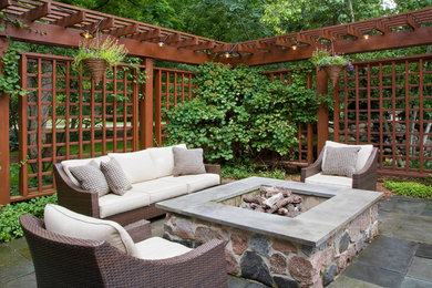 This is an example of a traditional backyard patio in Chicago with natural stone pavers, a pergola and a fire feature.
