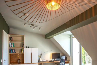 Modernes Arbeitszimmer mit grüner Wandfarbe, Teppichboden, Einbau-Schreibtisch und braunem Boden in München