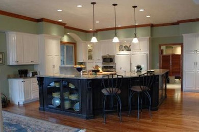 Example of a l-shaped light wood floor open concept kitchen design in St Louis with beaded inset cabinets, white cabinets, granite countertops, green backsplash, white appliances and an island